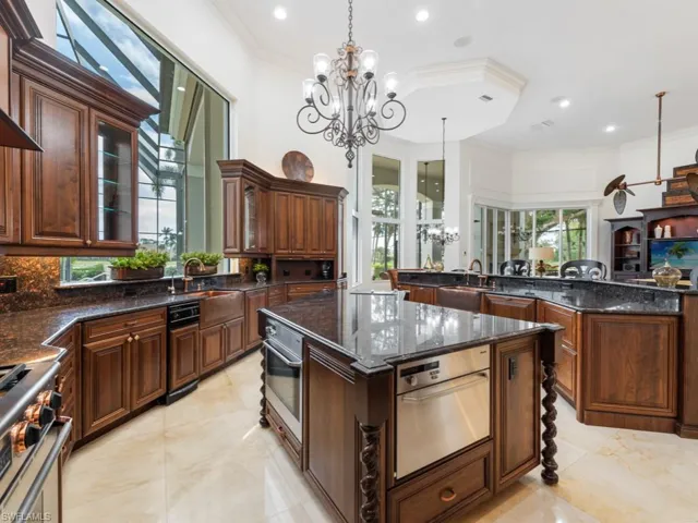 Kitchen with a chandelier, crown molding, stainless steel appliances, a kitchen island, and a sink
