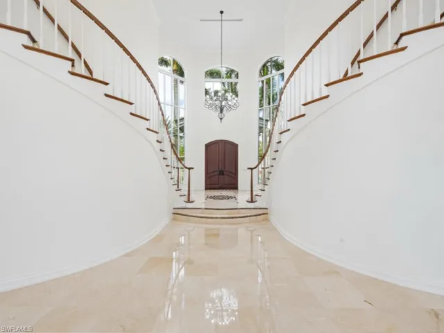 Entrance foyer featuring marble finish floor, stairs, a high ceiling, and baseboards