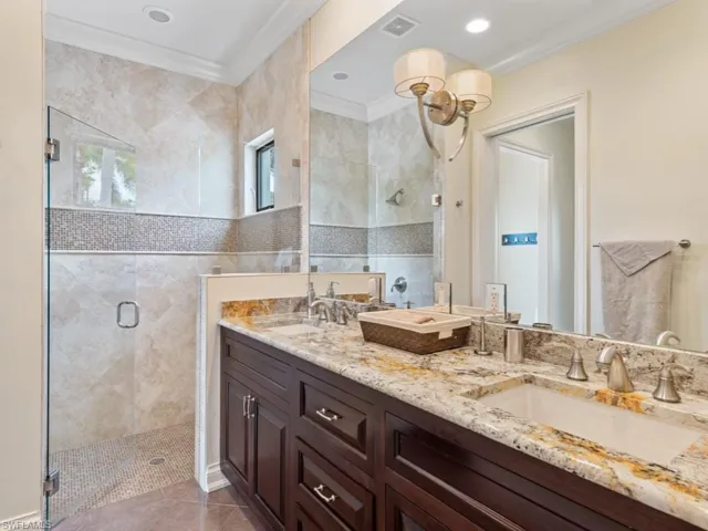 Full bathroom featuring a shower stall, visible vents, crown molding, and a sink