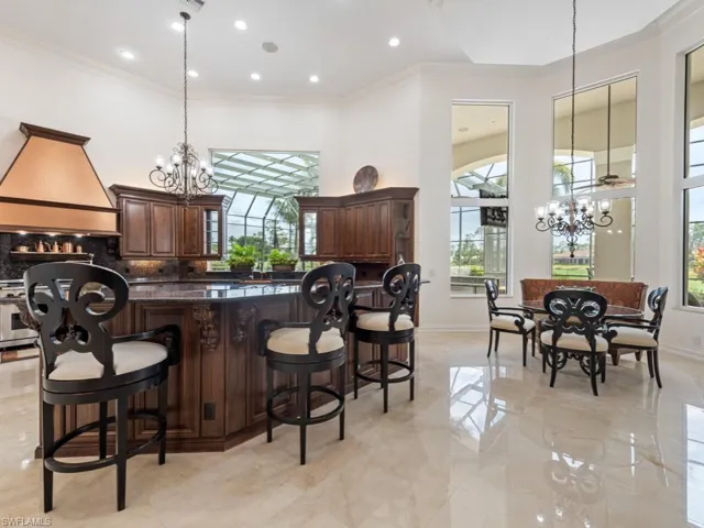Kitchen with custom range hood, ornamental molding, an inviting chandelier, and a healthy amount of sunlight