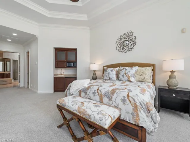 Bedroom with crown molding, baseboards, a sink, light carpet, and indoor wet bar