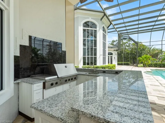 View of patio / terrace with an outdoor pool, a lanai, grilling area, a sink, and an outdoor kitchen