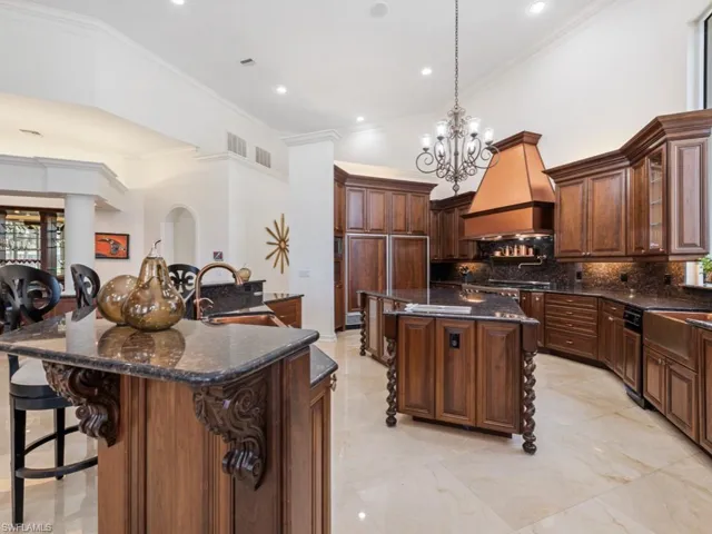 Kitchen with a large island with sink, tasteful backsplash, premium range hood, a towering ceiling, and a sink