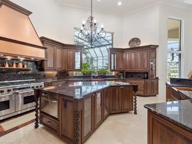 Kitchen featuring custom range hood, range with two ovens, a towering ceiling, and a chandelier