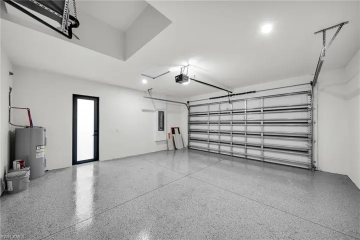 Garage with electric panel, electric water heater, and a garage door opener