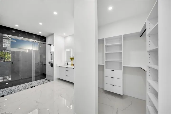 Bathroom with marble finish floor, a marble finish shower, recessed lighting, and vanity