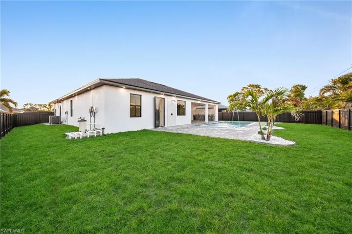 Rear view of house with a fenced backyard and a yard