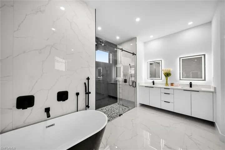 Full bath with marble finish floor, stone wall, a marble finish shower, double vanity, and recessed lighting