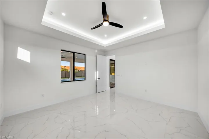 Spare room featuring a tray ceiling, baseboards, ceiling fan, and recessed lighting