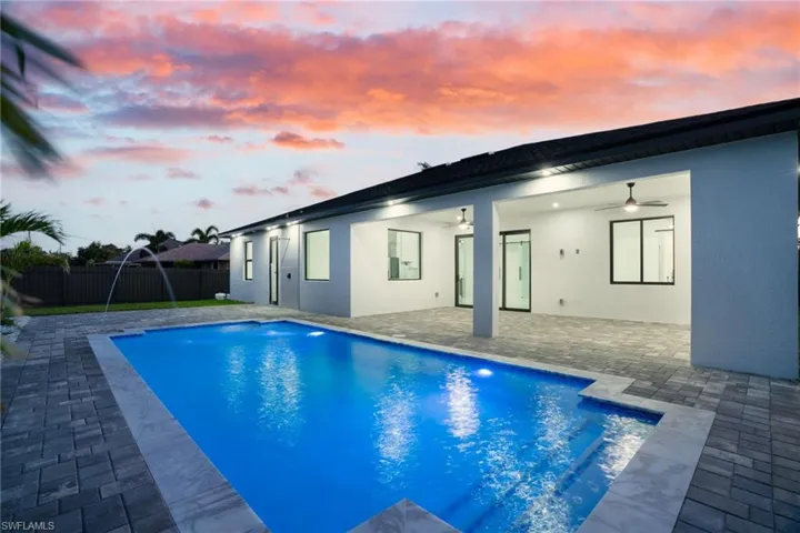 Pool at dusk with fence, ceiling fan, a patio, and a fenced in pool