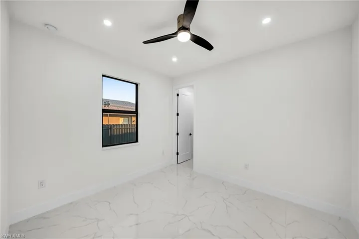 Empty room featuring marble finish floor, baseboards, and recessed lighting