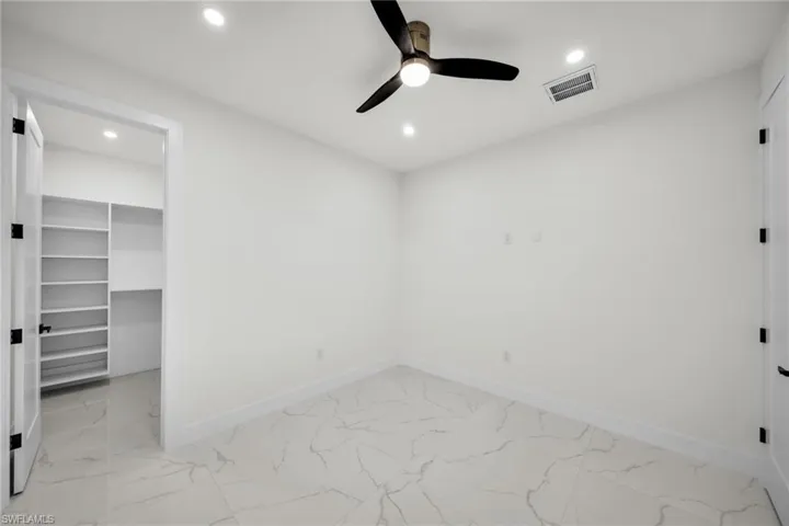 Unfurnished bedroom featuring a spacious closet, marble finish floor, baseboards, and visible vents