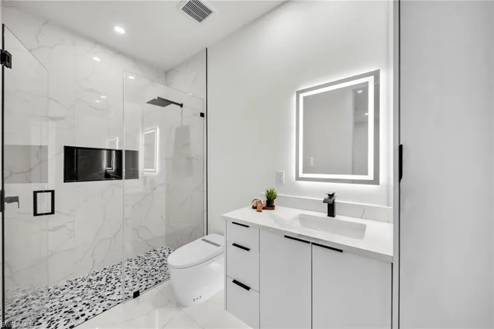Bathroom featuring marble finish floor, visible vents, toilet, and a marble finish shower
