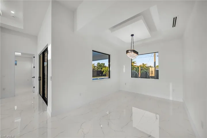 Unfurnished room featuring marble finish floor, baseboards, an inviting chandelier, and a raised ceiling