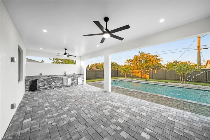 View of swimming pool featuring a fenced backyard, ceiling fan, an outdoor kitchen, and a patio area