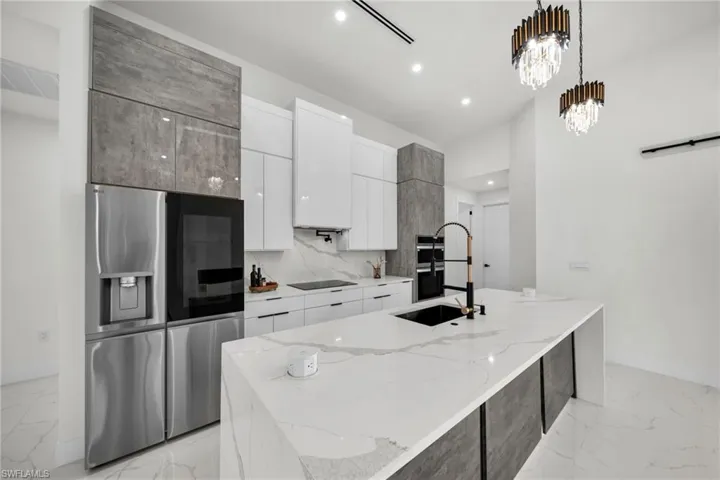 Kitchen with white cabinetry, marble finish floor, an island with sink, modern cabinets, and appliances with stainless steel finishes
