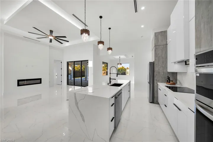 Kitchen with white cabinetry, stainless steel appliances, marble finish floor, a sink, and modern cabinets