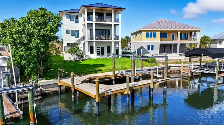 Dock area featuring boat lift, a lawn, a water view, and a residential view - Virtually Edited Image