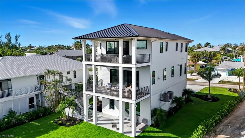 View of side of home featuring a yard, a patio area, a residential view, and a balcony - Virtually Edited Image