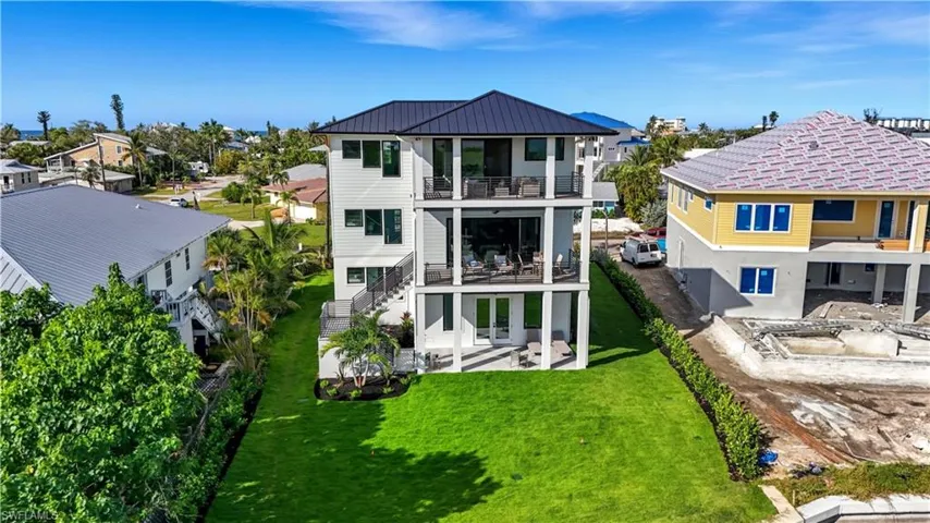 Rear view of property with a patio area, a residential view, stairway, a metal roof, and a balcony - Virtually Edited Image