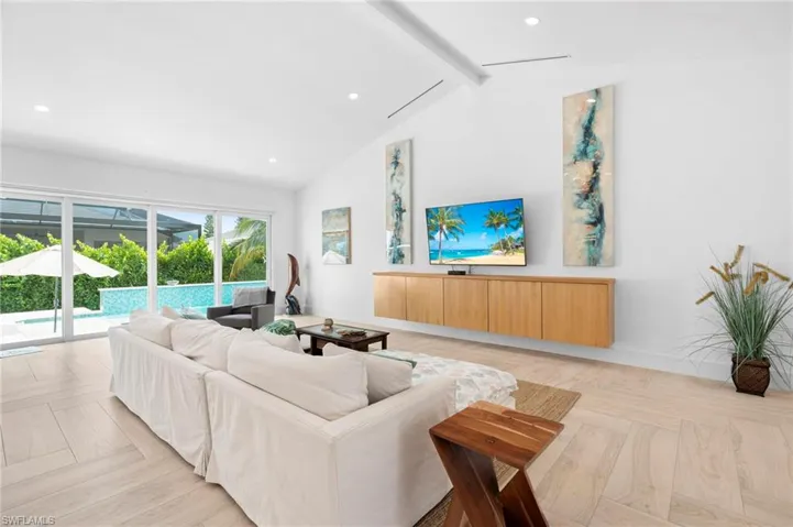 Living room with beamed ceiling, high vaulted ceiling, and light parquet floors