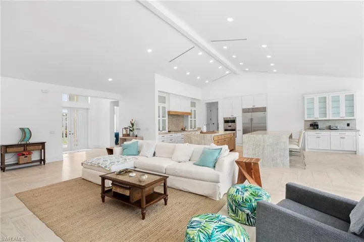 Living room with high vaulted ceiling, beamed ceiling, and light parquet floors