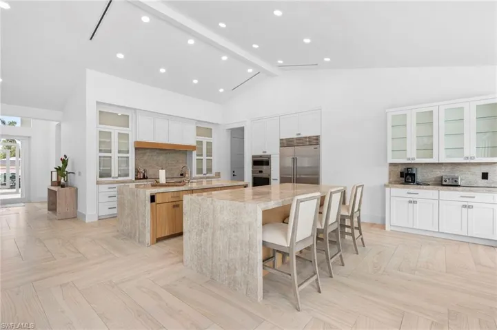 Kitchen with stainless steel built in refrigerator, a spacious island, beamed ceiling, and light parquet floors