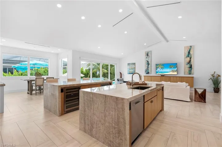 Kitchen with lofted ceiling with beams, sink, an island with sink, light parquet flooring, and beverage cooler