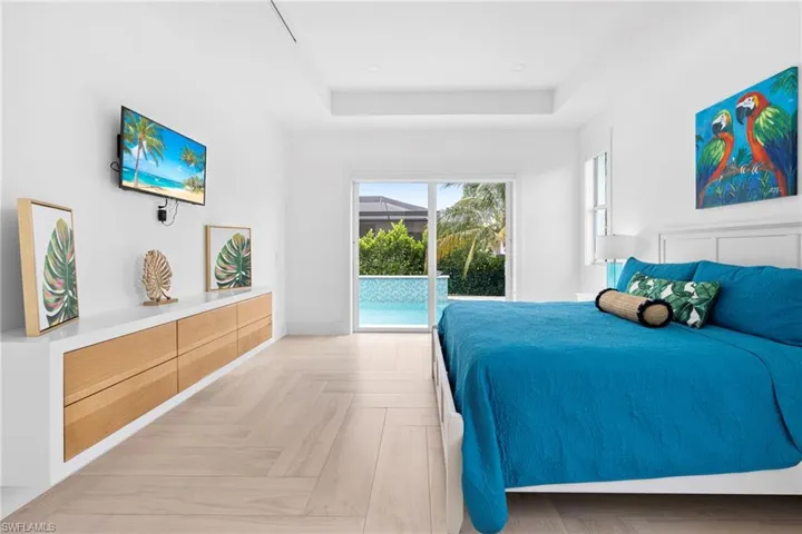 Bedroom with access to outside, a raised ceiling, and light parquet floors
