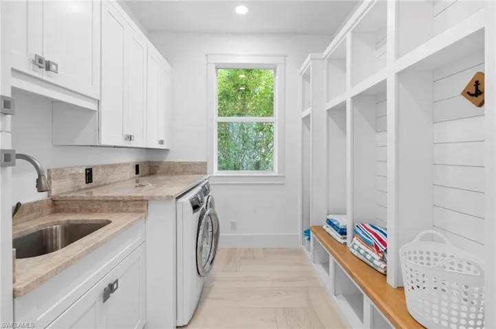 Washroom with sink, light parquet flooring, independent washer and dryer, and cabinets