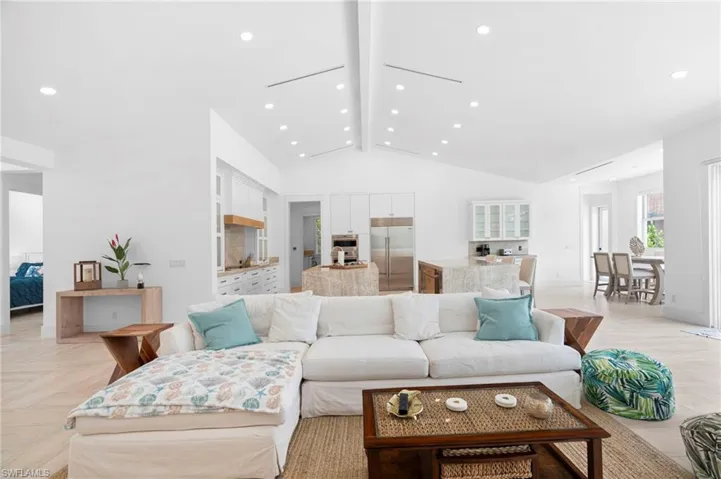Living room featuring beam ceiling, high vaulted ceiling, and light parquet flooring