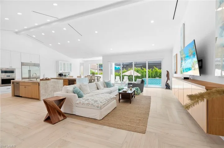 Living room with sink, high vaulted ceiling, beamed ceiling, and light parquet floors