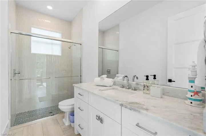 Bathroom featuring tile patterned flooring, toilet, vanity, and walk in shower