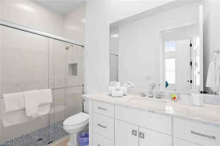 Bathroom featuring an enclosed shower, vanity, and toilet