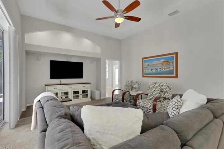 Living room with carpet floors, a ceiling fan, and a raised ceiling