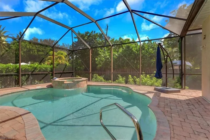 View of swimming pool featuring a sunroom, a lanai, a pool with connected hot tub, and a patio