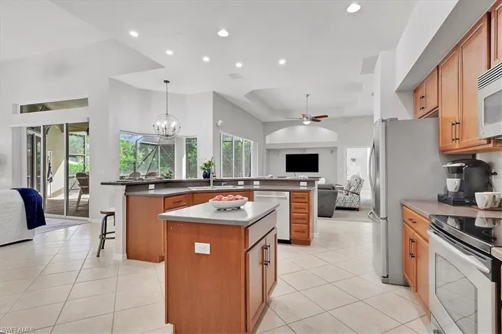 Kitchen featuring open floor plan, pendant lighting, light tile patterned floors, ceiling fan, and appliances with stainless steel finishes