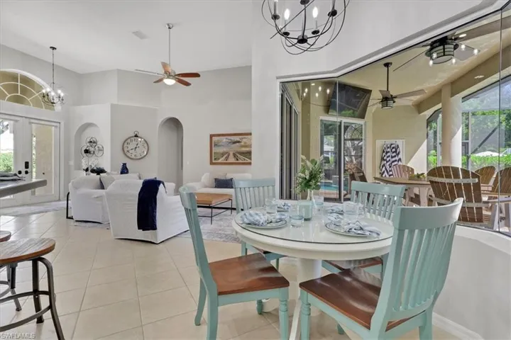 Dining space with a chandelier, ceiling fan, light tile patterned floors, arched walkways, and a high ceiling