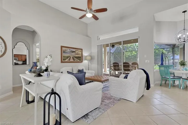 Living area featuring a sunroom, light tile patterned flooring, a towering ceiling, and ceiling fan