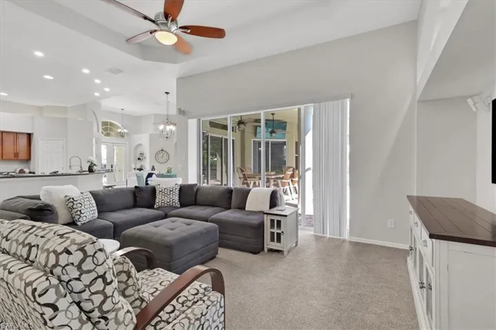 Living room featuring a ceiling fan, light colored carpet, recessed lighting, and a chandelier