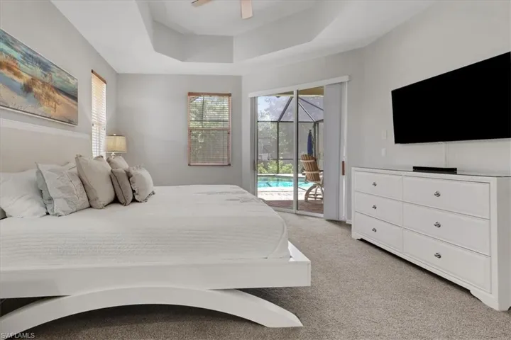 Bedroom with light colored carpet, access to outside, a raised ceiling, ceiling fan, and a sunroom