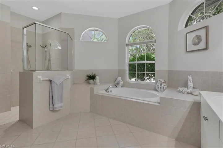 Bathroom featuring vanity, a walk in shower, a bath, and light tile patterned flooring