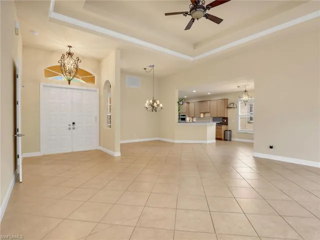 Foyer entrance featuring a chandelier, light tile patterned flooring, and a raised ceiling