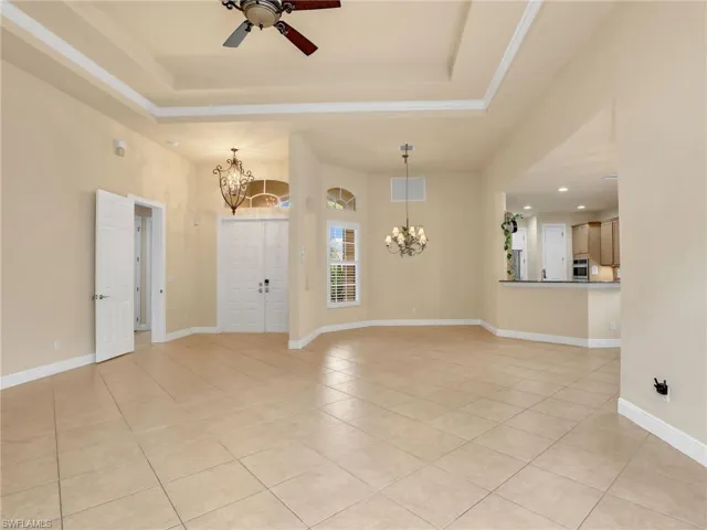 Unfurnished living room featuring a chandelier, light tile patterned floors, a raised ceiling, and recessed lighting