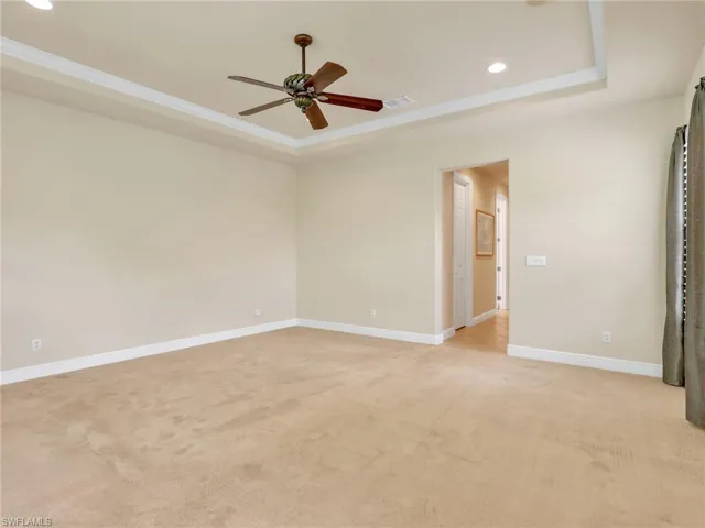Unfurnished room featuring a tray ceiling, recessed lighting, light carpet, ceiling fan, and crown molding