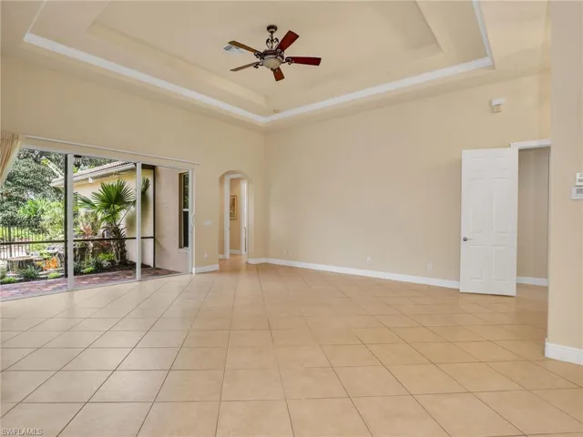 Spare room featuring a raised ceiling, light tile patterned floors, arched walkways, and a towering ceiling