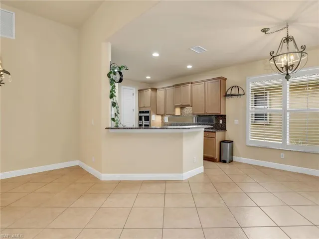 Kitchen with recessed lighting, light tile patterned flooring, a chandelier, decorative light fixtures, and decorative backsplash