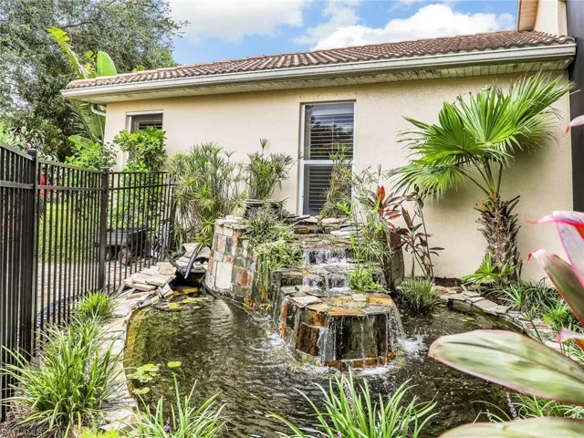 View of home's exterior with a small pond, stucco siding, and a tiled roof