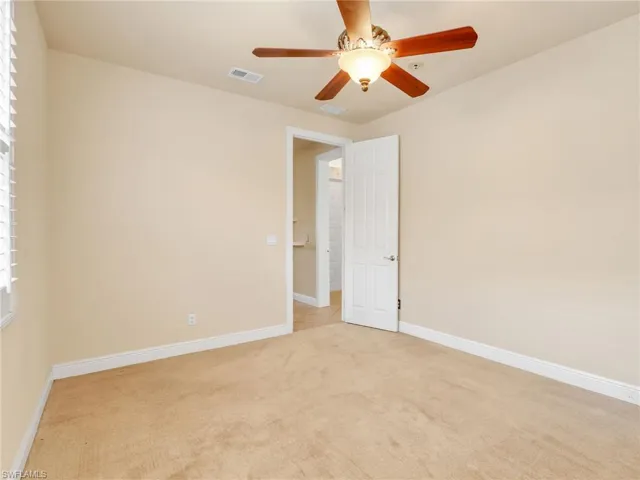 Empty room featuring light carpet and a ceiling fan