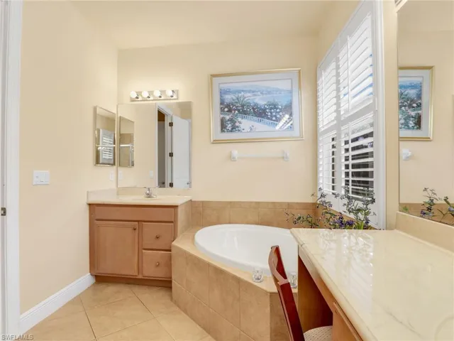 Bathroom with vanity, a garden tub, and light tile patterned floors